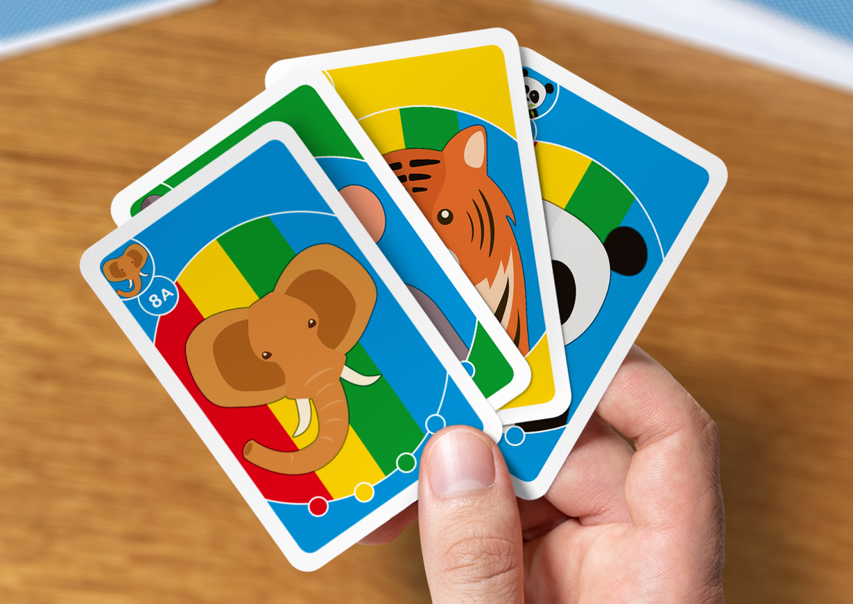 Eine Männerhand hält vier Kinderquartett-Karten mit Tiermotiven zwischen dem Daumen und dem Zeigefinger