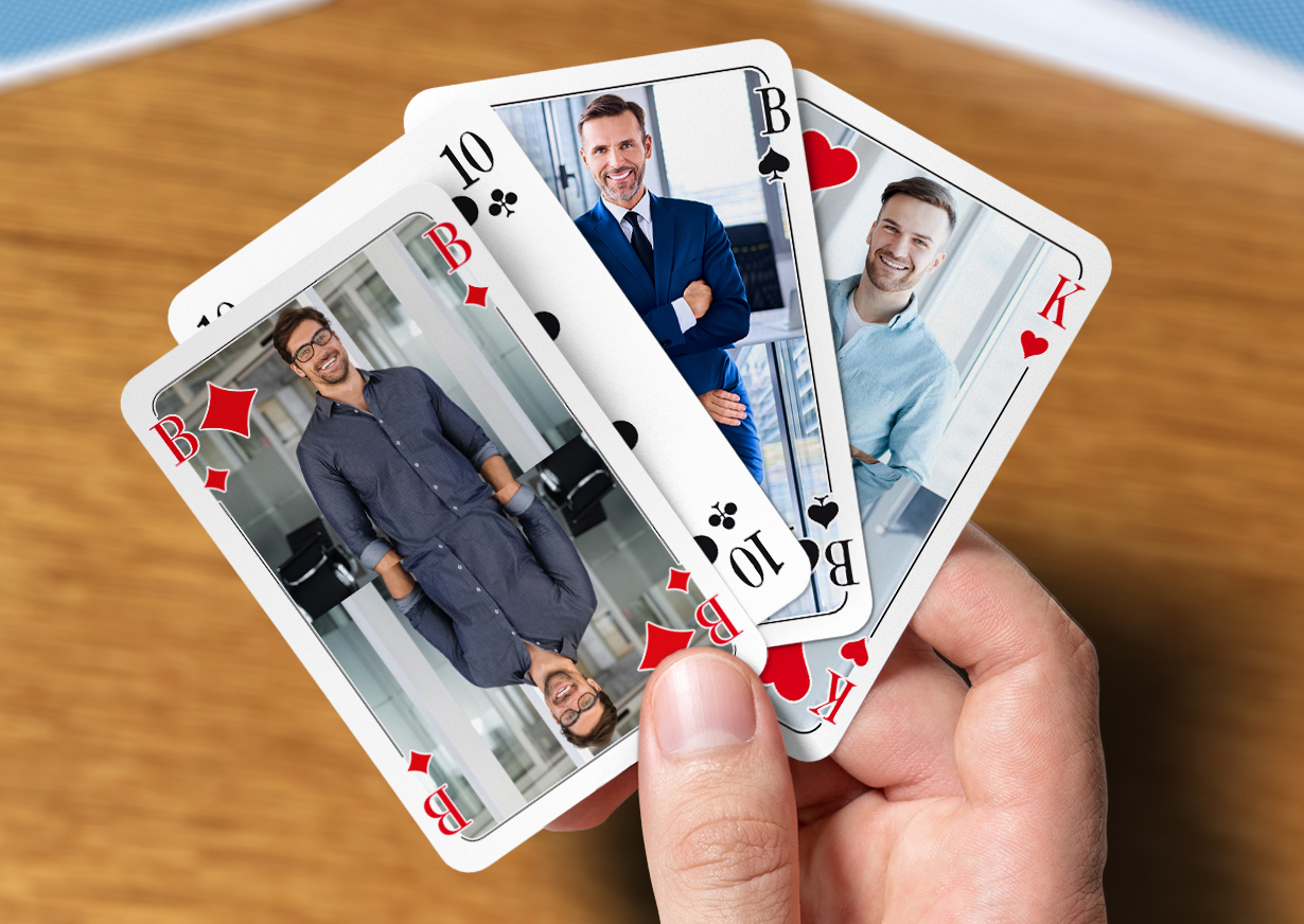 Eine Männerhand hält vier individuell gestaltete Skat Karten zwischen dem Daumen und dem Zeigefinger