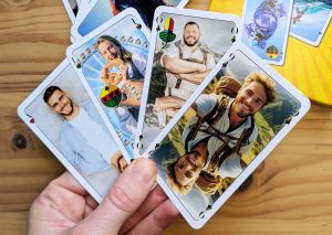 Auf einer Hand werden aufgefächert 4 Schafkopf-Karten gehalten mit eigenen Bildern auf den Karten.