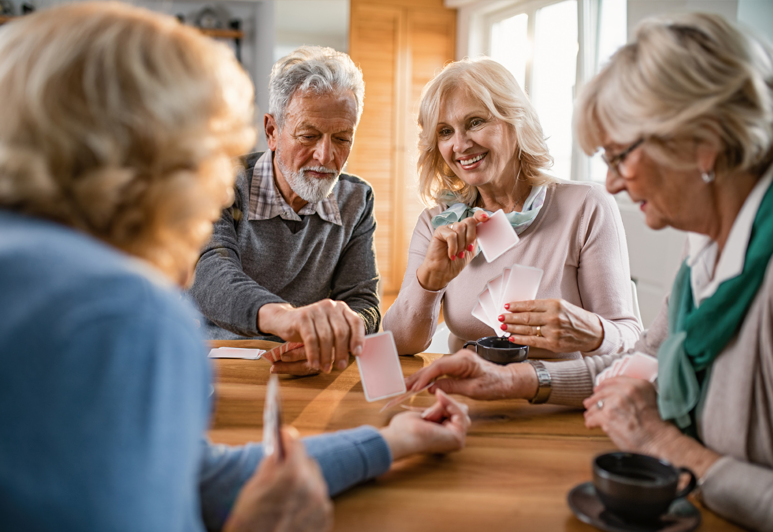 Eine Runde mit 3 Frauen und einem Mann sitzen an einem Tisch und spielen Karten