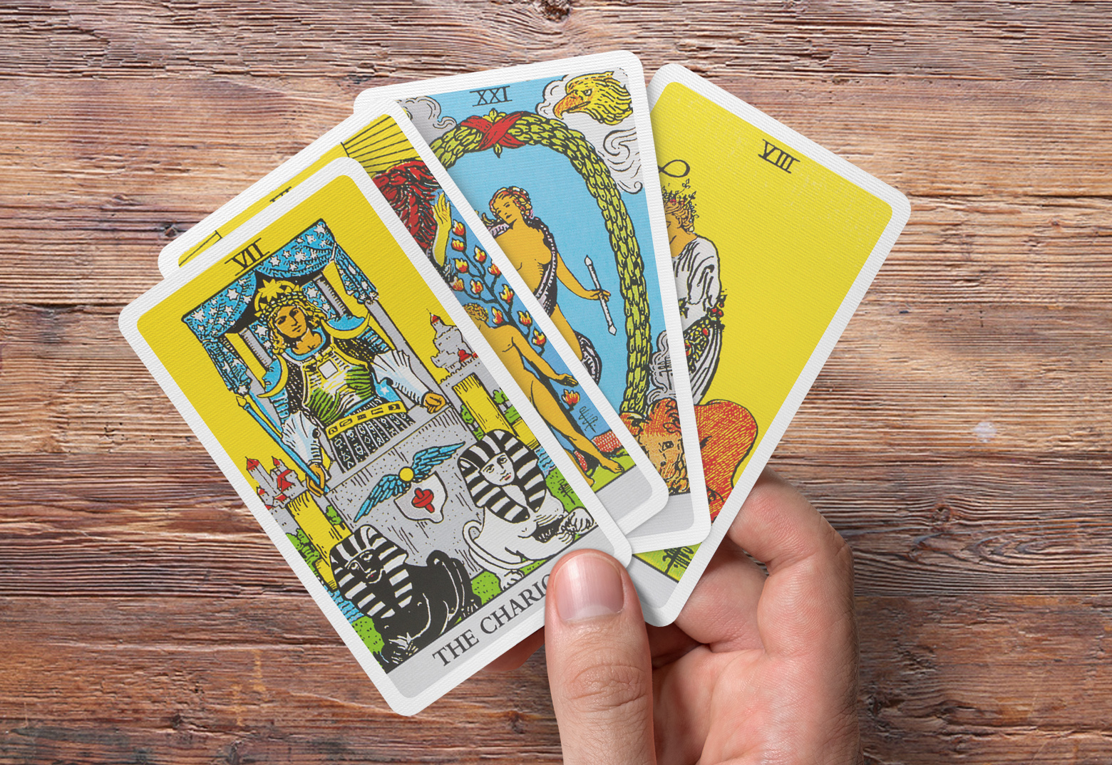 Eine Männerhand hält vier individuell gestaltete Tarot Karten zwischen dem Daumen und dem Zeigefinger