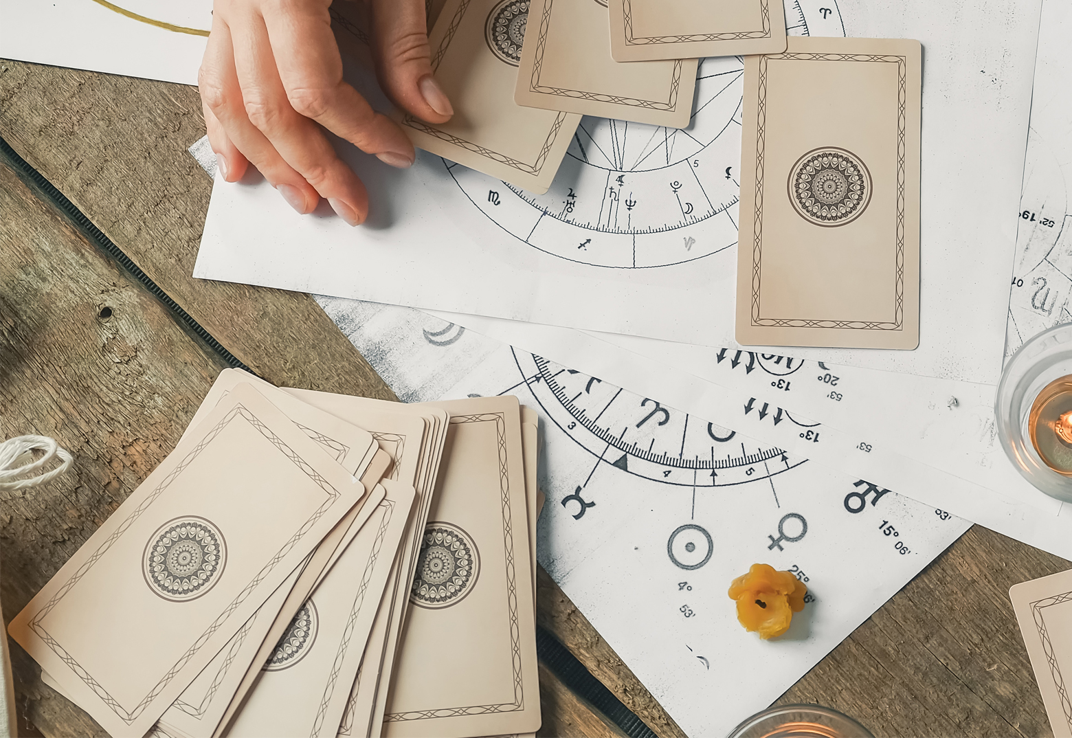 Tarot Karten und Symbole liegen auf dem Tisch. Die Hand einer Frau ist zu sehen.