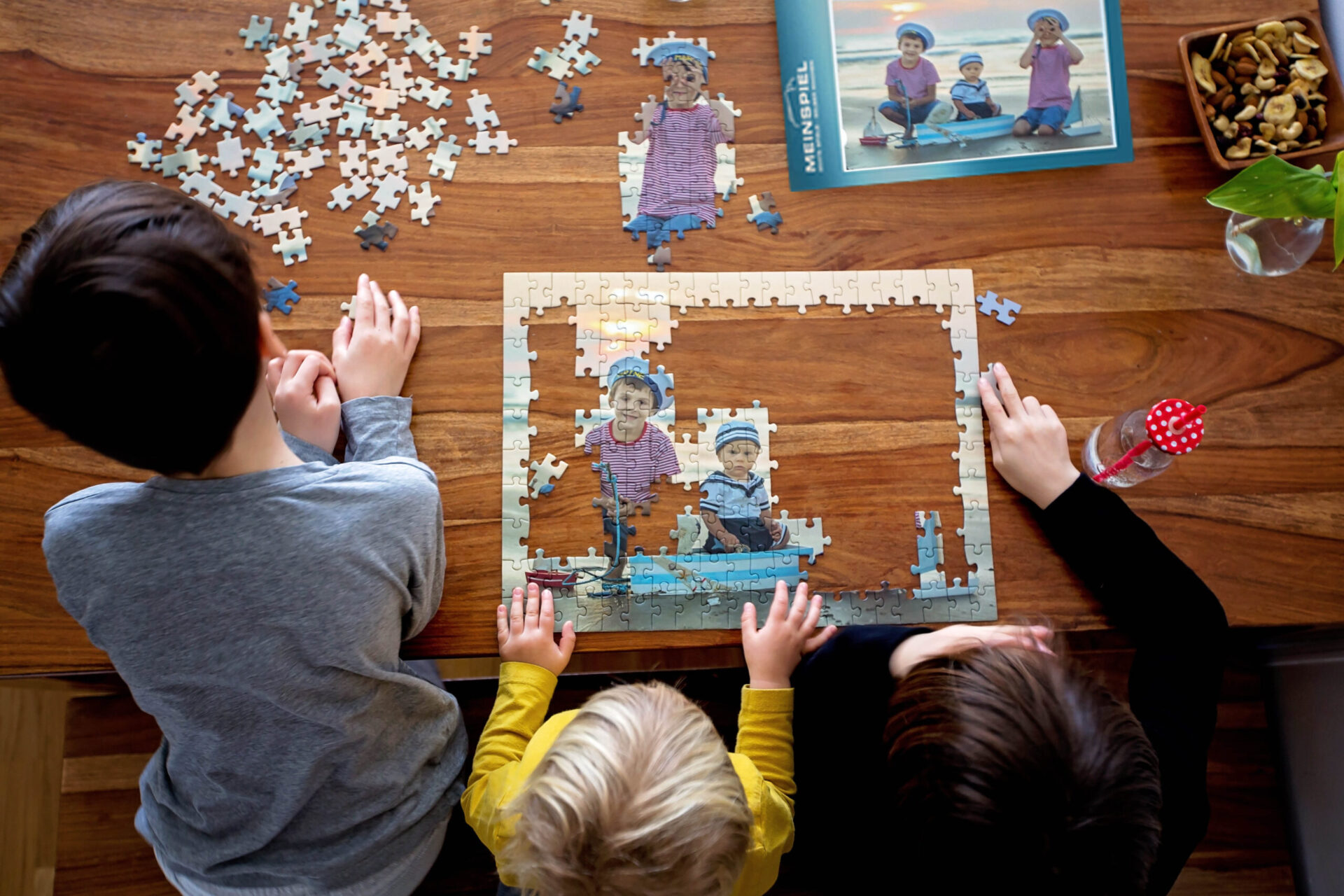 3 junge Kinder die ein Puzzle mit ihrem Bild vom Strand zusammensetzen
