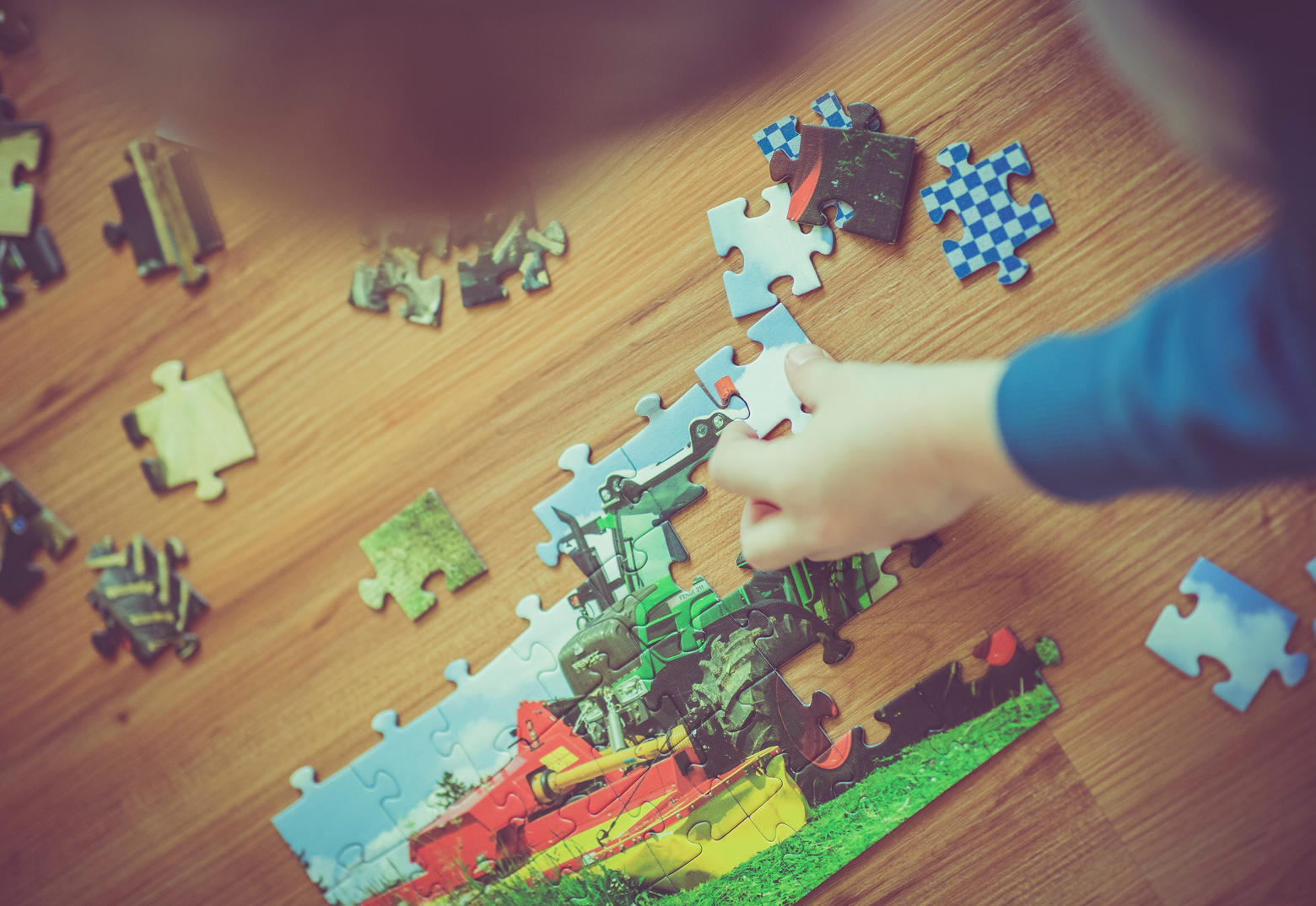 Ein Kind baut das Fotopuzzle, auf dem ein Trecker abgebildet ist, zusammen