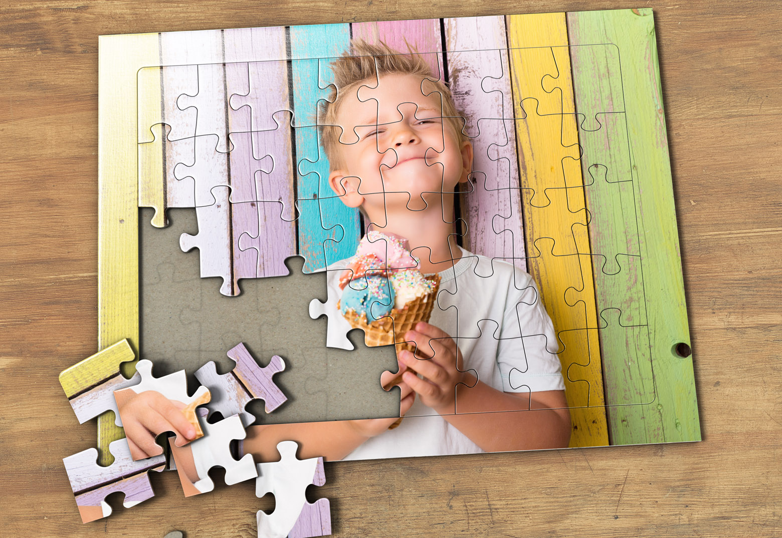 Auf einem Holztisch ist ein individuell gestaltetes Fotopuzzle bei MeinSpiel mit einem Jungen, der ein Eis isst, als Motiv zu sehen