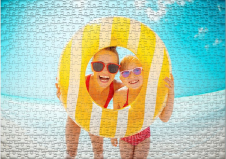 Auf dem Fotopuzzle ist eine Frau mit Ihrer Tochter im Urlaub am Strand mit einem Schwimmreifen zu sehen